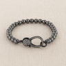 Auria Bracelet — polished hematite beaded bracelet with pavé crystal clasp on linen background, modern jewelry by Matte.