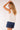 Back view of Yui Sleeveless Ruffle Detail Top with gathered detail, paired with casual denim shorts.
