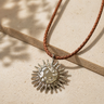 Bartu Necklace sun pendant necklace with braided cord on neutral textured background, showing radiant sun design and warm boho style.