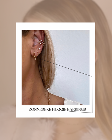 Close-up of an ear wearing gold earrings with a blurred background