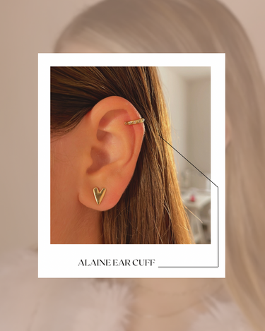 Gold plated ear cuff worn by a person with blurred background