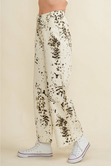 Biz Pants wide-leg printed trousers shown in side profile, featuring high-rise waistband, fluid wide-leg silhouette, and black abstract print detail on ivory fabric with sneakers styling.