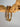 Stack of gold and silver Blasco Bracelets displayed on natural wood branch