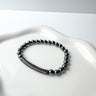 A black and silver beaded stretch bracelet displayed on a white surface by matte jewelry