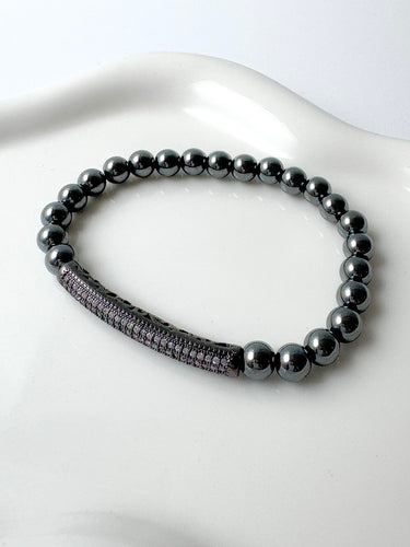 Close-up of Blossomen Bracelet with polished hematite beads and pavé crystal bar on ceramic background