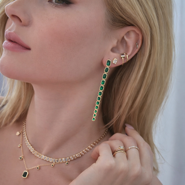 Blow Stud Earrings worn on model with sleek hair, showcasing long green stone drop design.
