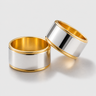 Bolty Ring two-tone silver and gold wide band rings on neutral background, showing mirror-finish surface and warm gold lining.