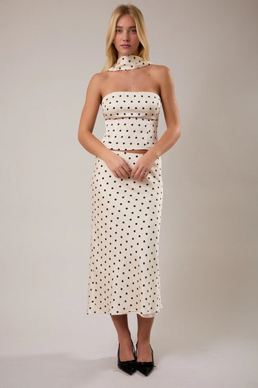 Woman wearing a strapless polka dot shirt  against a plain background