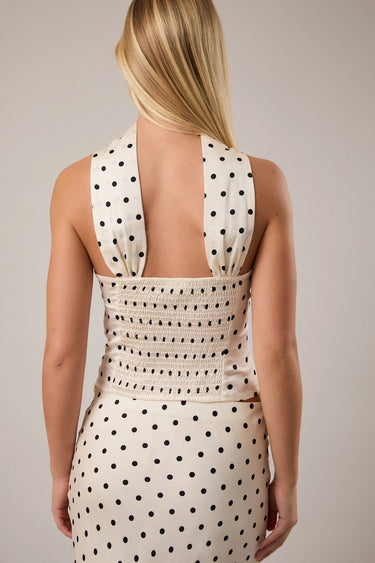 Woman wearing a polka dot shirt with a plain background