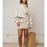 Woman wearing boxy cropped hoodie and matching mini skirt in soft neutral tones, front view.