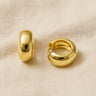 Gold domed huggie earrings on beige linen backdrop — Cairo Huggie Earrings by Matte.