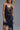 Black satin slip dress with delicate lace trim and fluid silhouette, shown on model layered with gold jewelry — Cala Dress by Matte.
