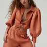 Model wearing Camille Blouse in terracotta organic linen with puff sleeves, close up — Matte Concept Store