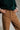 Person wearing brown pants and a green sweater with a neutral background