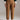 Front view of caramel relaxed fit cotton trousers with mid-rise waist and ankle length, styled with sneakers and green sweater