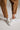 Hem detail of caramel relaxed fit cotton trousers with cuffed ankle and white sneakers, casual everyday style
