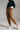 Side angle view of caramel relaxed fit trousers with rolled hem and ankle length, paired with sneakers