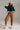 Full body look of caramel relaxed fit cotton trousers styled with green sweater, white sneakers, and cap for casual chic outfit