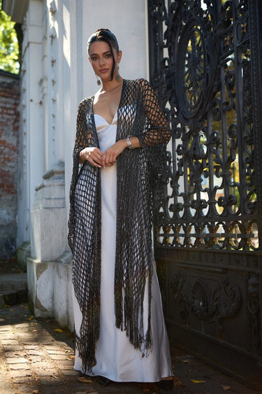 Chalat Kimono worn by model, full body view outdoors, showing light-catching crochet knit and long fringed silhouette