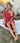 Cisne Lightweight Resort Cover Up coral version seated outdoors highlighting airy silhouette
