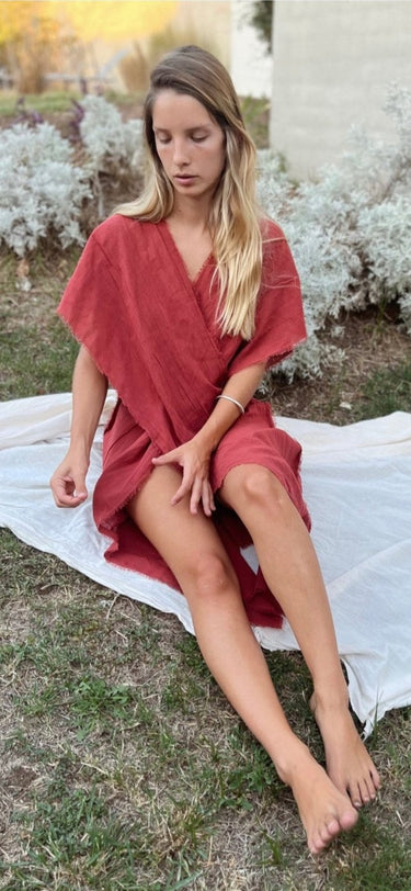 Cisne Lightweight Resort Cover Up coral version seated outdoors highlighting airy silhouette