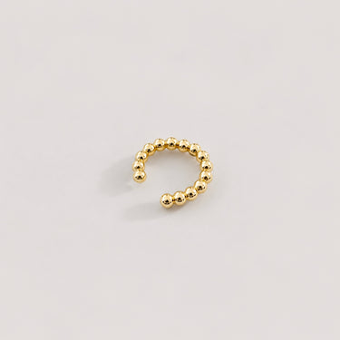Claude Ear Cuff in polished gold featuring a rounded beaded open cuff design, styled as a sleek minimalist ear cuff on a soft neutral background.