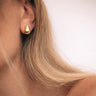 Cleat Stud Earrings gold teardrop stud earrings worn on ear minimal sculptural styling.
