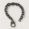 Coil Bracelet — black mirrored chain bracelet with pavé crystal clasp on linen background, bold and modern statement piece by Matte.