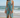 Model wearing turquoise sarong with coral tropical print tied as a beach wrap, standing by the ocean.
