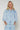Model wearing the Corsica light-wash denim blouse with volume sleeves.

