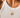 Debon Gold Charm Necklace worn on neck with layered gold chain, featuring cross, heart, and green stone charms on warm skin tone.
