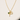 Debon Gold Charm Necklace close-up on neutral background showing gold cross, open heart, and emerald green stone details.