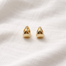 Ela Huggie Earrings – geometric gold huggie earrings with a sculptural triangular design, photographed on a soft neutral fabric background.