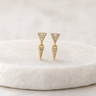 Gold triangle-shaped earrings with embedded stones on a white cushion