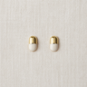 Gold capsule-shaped stud earrings on neutral linen background – Elodie Stud Earrings by Matte