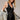 Woman wearing the Ephesus Bodysuit in black with bold metallic embroidery and a fitted V-neck silhouette, photographed in soft natural light on a neutral backdrop.
