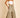A female model wearing a white tube top and green wide leg pants with a high waist and tiered design.
