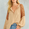 Woman wearing Evalina Blouse in beige silk with embroidered animal-texture sleeves, styled with denim jeans.