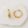 Fira Huggie Earrings — gold plated huggies with sculpted heart details on white linen background, lightweight and romantic jewelry by Matte.