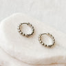 Pair of silver Francesca mini huggies earrings on a white stone surface