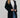 Woman wearing long black trench coat over jeans and white top, styled with tan hat – Matte Outerwear Collection