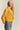 Model wearing mustard cropped coat styled with ankle boots, relaxed casual outfit