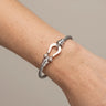 Haddy Bangle Bracelet silver twisted cable bracelet worn on wrist with polished horseshoe clasp detail, modern stainless steel cuff design with sleek luxury finish and minimalist styling.**
