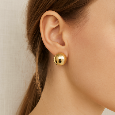 Halott Huggie Earrings in gold worn on ear showing compact polished huggie style.