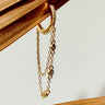 A gold-filled hoop earrings with a chain and small pave crystals, displayed on a wooden surface.