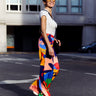 Model wearing multicolor geometric print wide-leg pants with white tee — vibrant resort look.
