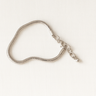 Helios Bracelet — sleek snake-style bracelet in gold or silver with lobster clasp and mirror-polished finish, photographed on beige linen background, Matte Jewelry Collection.