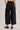 Back view of High-Rise Pleated Culotte Pants in black with pleated wide leg and cuffed hem