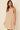 Model wearing beige Holli Dress with halter neckline and flowy silhouette.