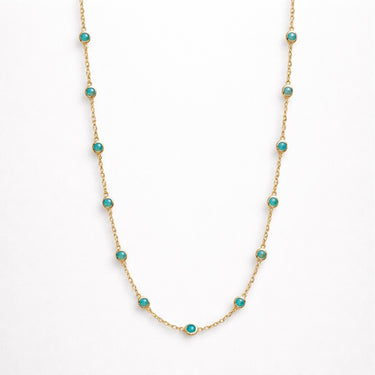 Iki Necklace turquoise version flat lay showing vibrant blue-green stones set in gold chain arranged symmetrically on neutral background